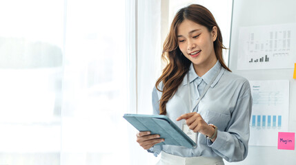 Confident businesswoman in suit reading business data on tablet