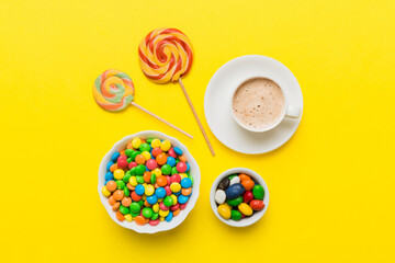 Coffee cup with chocolates and colored candy. Top view on table background with copy space