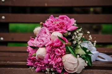 Two gold wedding rings on a bouquet of pink peonies