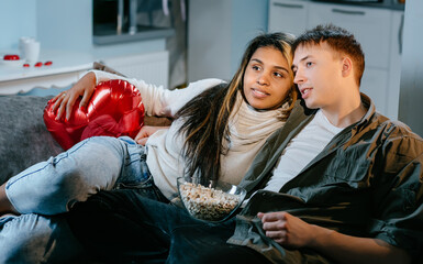 Fototapeta na wymiar An young couple in love are watching movies on a TV,