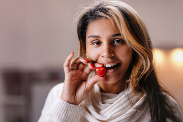 Women's hands with a bright manicure hold a heart-shaped chocolate candy