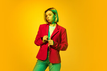 Young charming girl with blonde hair wearing red jacket posing over yellow background. Concept of youth, student college life, business and education