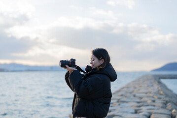 Obraz premium 夕暮れの海で写真を撮る女性