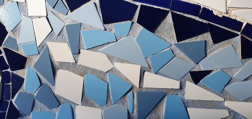 Wall made of pieces of broken tiles. Broken tiles background. Mosaic tiles. Pattern of tile pieces. Blue-white background. Mosaic texture.