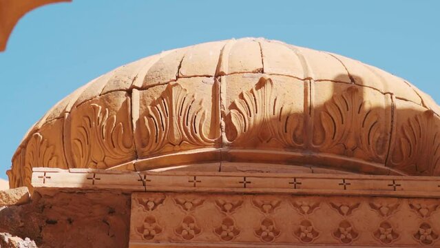 Closeup shot of carvings on the top portion of the chattri dome cenotaph at Bada Bagh in Jaisalmer, Rajasthan, India. Carvings on top of the structure made out of sandstone. Ancient carving on dome. 