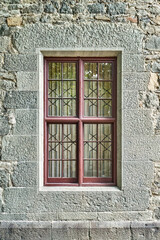 Old windows with wrought iron grating on stone wall of historical building. Medieval castle with restored walls attracts arriving visitors attention © timltv