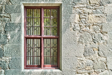 Old windows with wrought iron grating on stone wall of historical building. Medieval castle with restored walls attracts arriving visitors attention © timltv