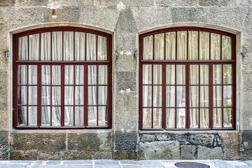 Old arched windows with white curtains on stone wall of historical building. Medieval castle with restored walls attracts arriving visitors attention © timltv