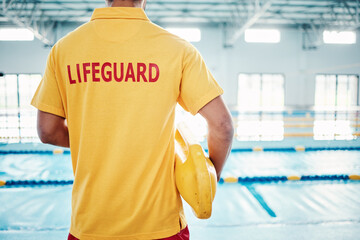 Security, safety or lifeguard by a swimming pool to help rescue the public from danger or drowning in water. Back view, trust or man standing with a lifebuoy ready with reliable assistance or support - obrazy, fototapety, plakaty