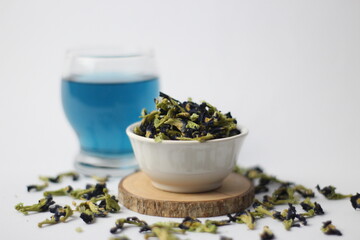 Dried Telang flower or Butterfly pea flower or commonly called in Indonesia 'Telang' Flower (Clitoria ternatea), with a glass of butterfly pea tea. Selective focus.