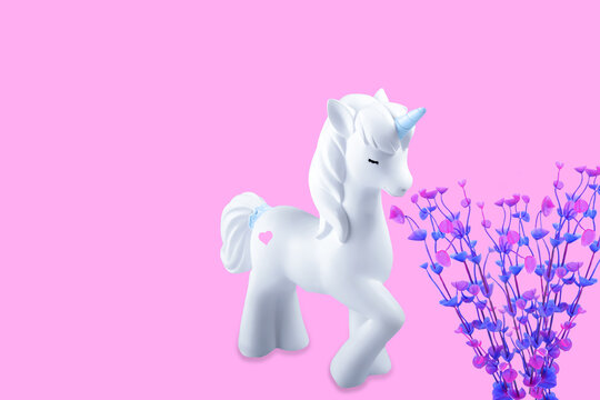 Creative composition unicorn in love with the flowers and heart. Pastel pink background.