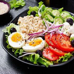 Healthy breakfast. Savory oatmeal with fresh cucumber, tomatoes, olives, lettuce, mozzarella cheese and boiled egg. Top view