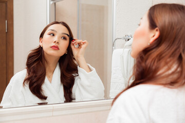 Obraz na płótnie Canvas Closeup of asian woman applying mascara on eyelashes