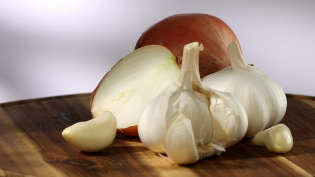onions and garlic on a cutting board. a clove of garlic and half an onion lie with the whole. vegetables ready for cutting close-up. kitchen on a sunny day. High quality 4k footage