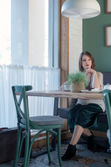 Young attractive woman in cafe looking at camera. Business meeting. Lonely woman sits in cafe with cup of coffee or tea.