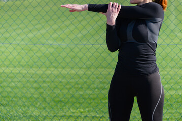 Athlete woman with sporting a black suit training on a in outdoor on the sunny day. Concept of healthy lifestyle and street workout.