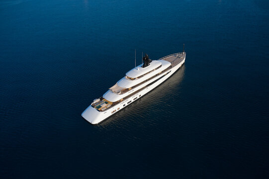 White mega yacht at sunset top view. Large innovative modern yacht anchored in the open sea aerial view.
