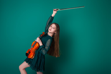 A girl in a green dress plays the violin on a plain green background.