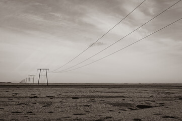 stony desert in Iceland - a striking black and white portrayal of man's impact on the rugged terrain. The powerlines serve as a symbol of progress amidst the unchanging landscape.