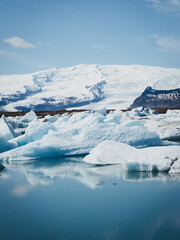 Drifting ice sculptures on a glacier in Iceland, set against a breathtaking backdrop of snow-capped mountains, capturing the beauty and majesty of this frozen landscape on a brilliant day © Stephan