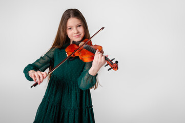 A girl in a green dress plays the violin on a white background.