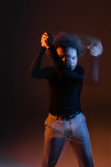 long exposure of wounded african american man with bipolar disorder on dark background with orange and blue light