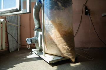 Vacuuming sawdust while sawing wood. Chip blower in furniture production.