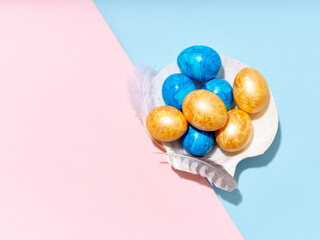 Creative layout with colored easter eggs arranged in a seashell on bright blue and pink background. A template for festive content