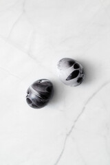 Easter egg decorating ideas. Two eggs painted marble on white background. Minimal Easter concept with space for text. Black monochrome luxury backdrop.