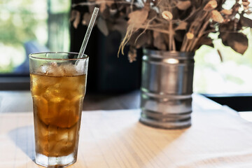 Beautiful still life with dried flowers in a tin vase and a long Island cocktail on the table by the window