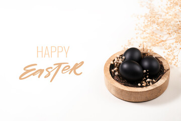 Eggs painted black on white background. Nest containing three egg with gypsophila flowers. Happy...