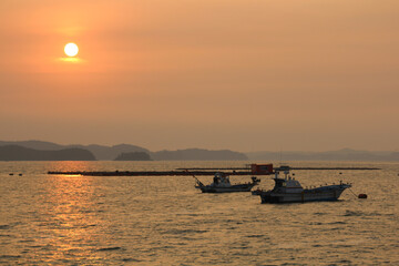 A fishing boat returning from the sea at sunset.