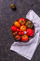 The harvest of assorted tomatoes. Colorful organic tomatoes on a large dish. Tomatoes different varieties. Top view