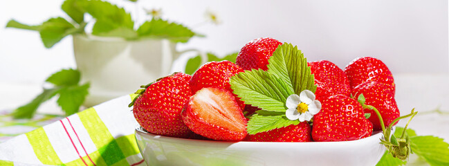 Strawberries in white porcelain bowl on a table. Bowl filled with juicy fresh ripe red...