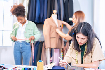 Attractive Young Asian woman professional fashion designer checking finished cloth in studio room