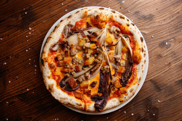 The top view of delicious Italian untypical gourmet vegetarian pizza with mozzarella, pumpkin, walnuts, red radicchio on the wooden background 