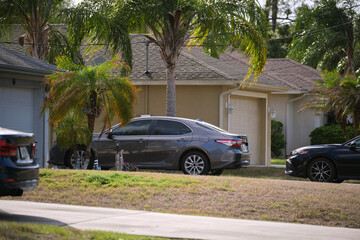 Car parked in front of wide garage double door on concrete driveway of new modern american house