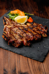 top view of delicious ribeye beef steak on the ribbon on the black stone plate with carrots slices