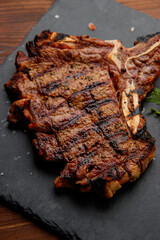 top view of delicious ribeye beef steak on the ribbon on the black stone plate  in the wooden backgrounds 