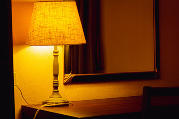 A close up shot of a dimly lit lamp shade in a hotel room 