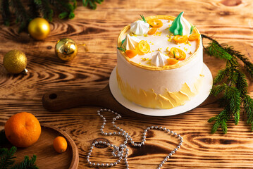 delicious white cake with orange and spruce twigs on wooden sawn wood. christmas decoration. atmospheric photo