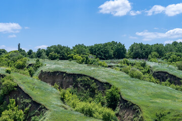 View ravine covered with greenery. Landscape valley with geological faults. Earthen mountains and...