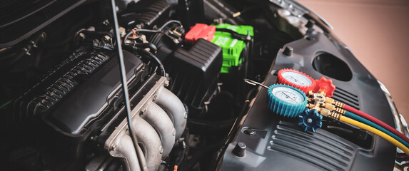 Car care maintenance and servicing, Close-up measuring manifold gauge on car engine for check refrigerant and filling air conditioner to fix repairing heat conditioning compressor system.