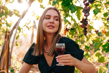 Young blonde woman sitting on a picnic in a vineyard