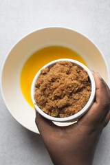 Brown sugar in a ramekin in a woman's hand, sugar for baking in a ramekin