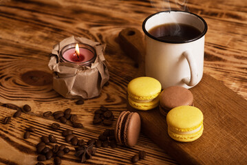 Sweet macaroons on wooden board with cup of coffee and a burning candle. Atmospheric photo. Content for social networks