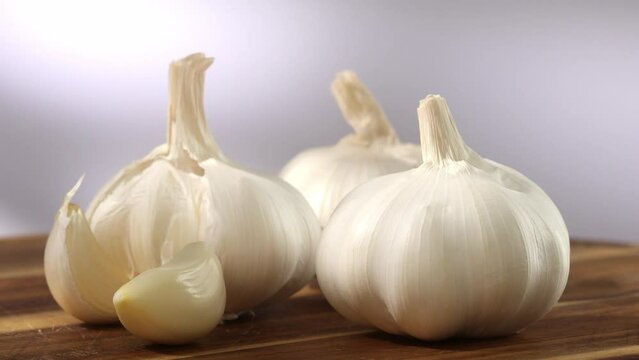 garlic on a cutting board. garlic clove along with whole ones on a gray background. vegetables ready for cutting close-up. kitchen on a sunny day. High quality 4k footage