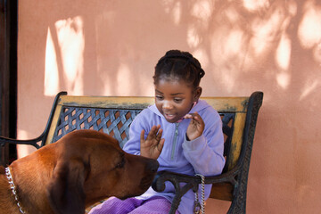 african girl with her dog on the bench outdoors