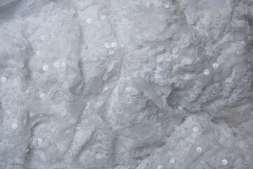Elegant white fabric. Wavy white lace drape with small paiettes. Close up of the cloth.