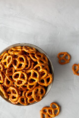 Mini Pretzels with Salt in a Bowl on a gray surface, top view. Flat lay, overhead, from above. Copy space.